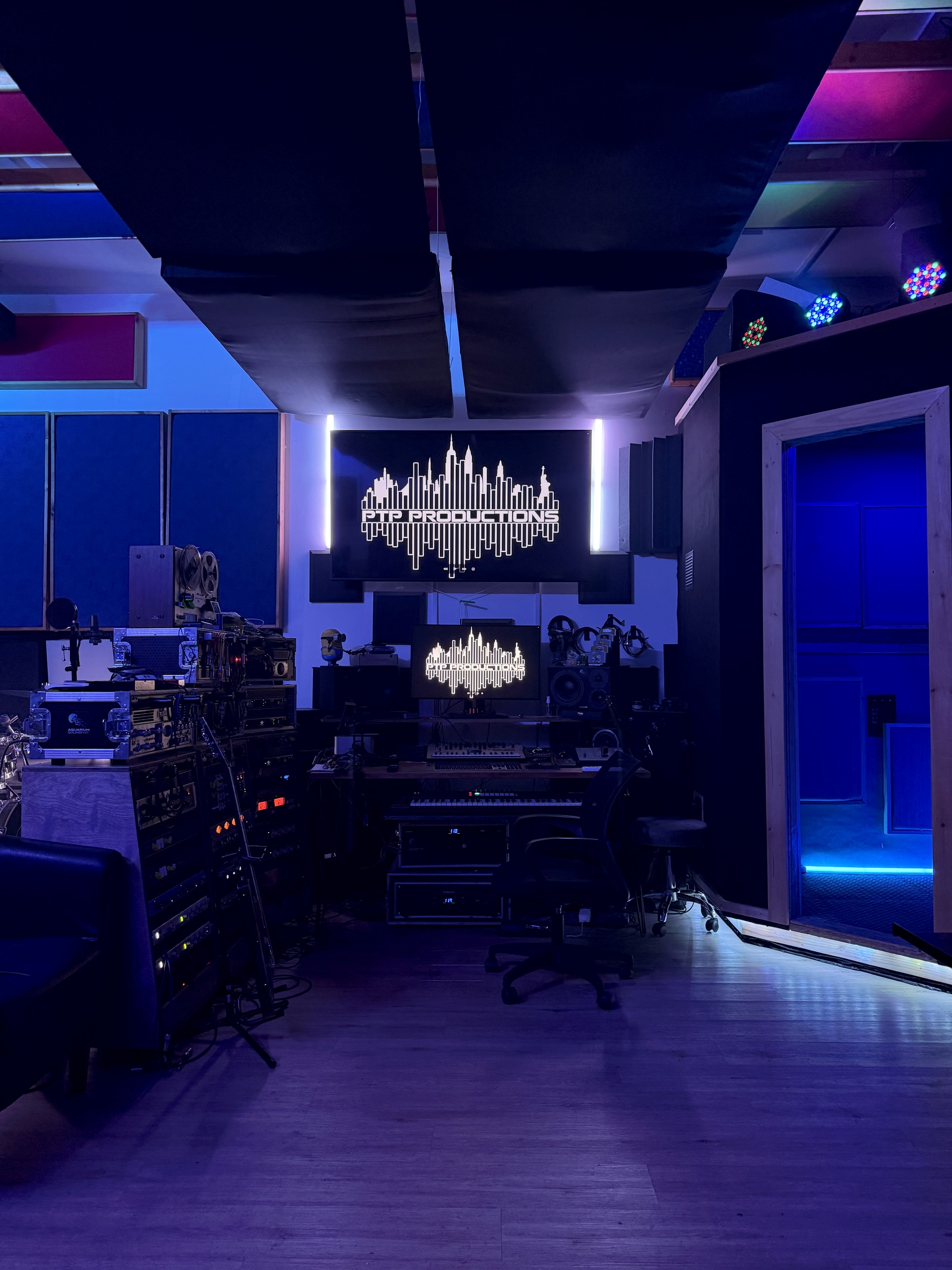 Control room with PTP Productions wordmark, mixing desk, keyboards and outboard racks