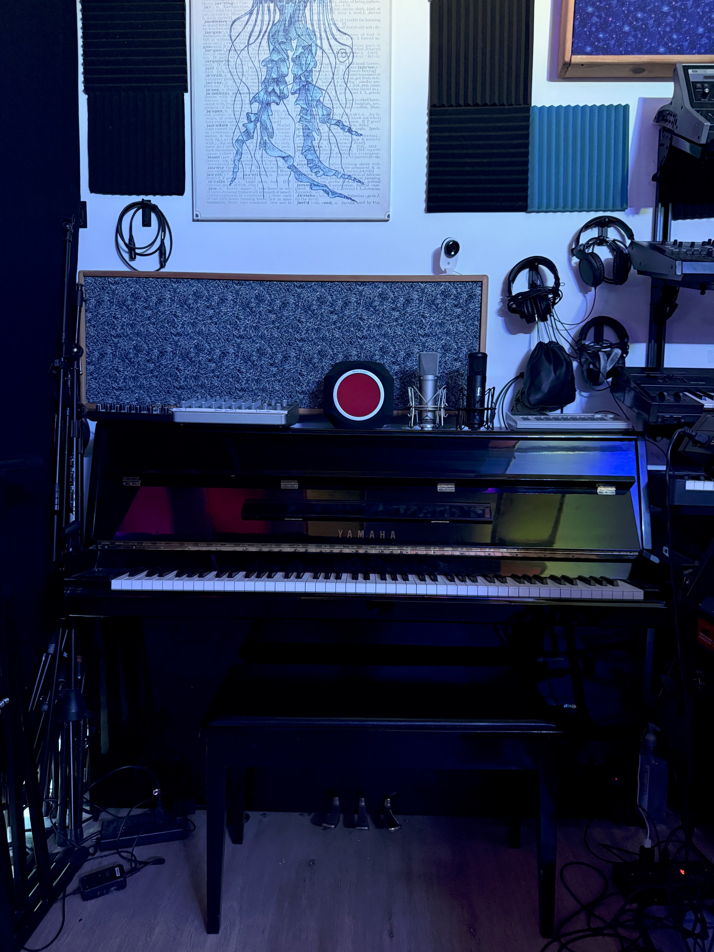 Yamaha upright piano with headphones, sheet music holder, and acoustic foam treatment
